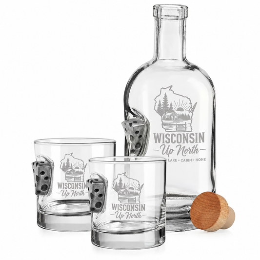 A clear glass decanter and two matching lowball glasses with dice-shaped metal accents, plus a wooden stopper, all printed with a Wisconsin state outline and the words 'Wisconsin Up North' on a white background.
