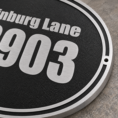 Close-up of textured black cast aluminum address sign with raised silver border and lettering