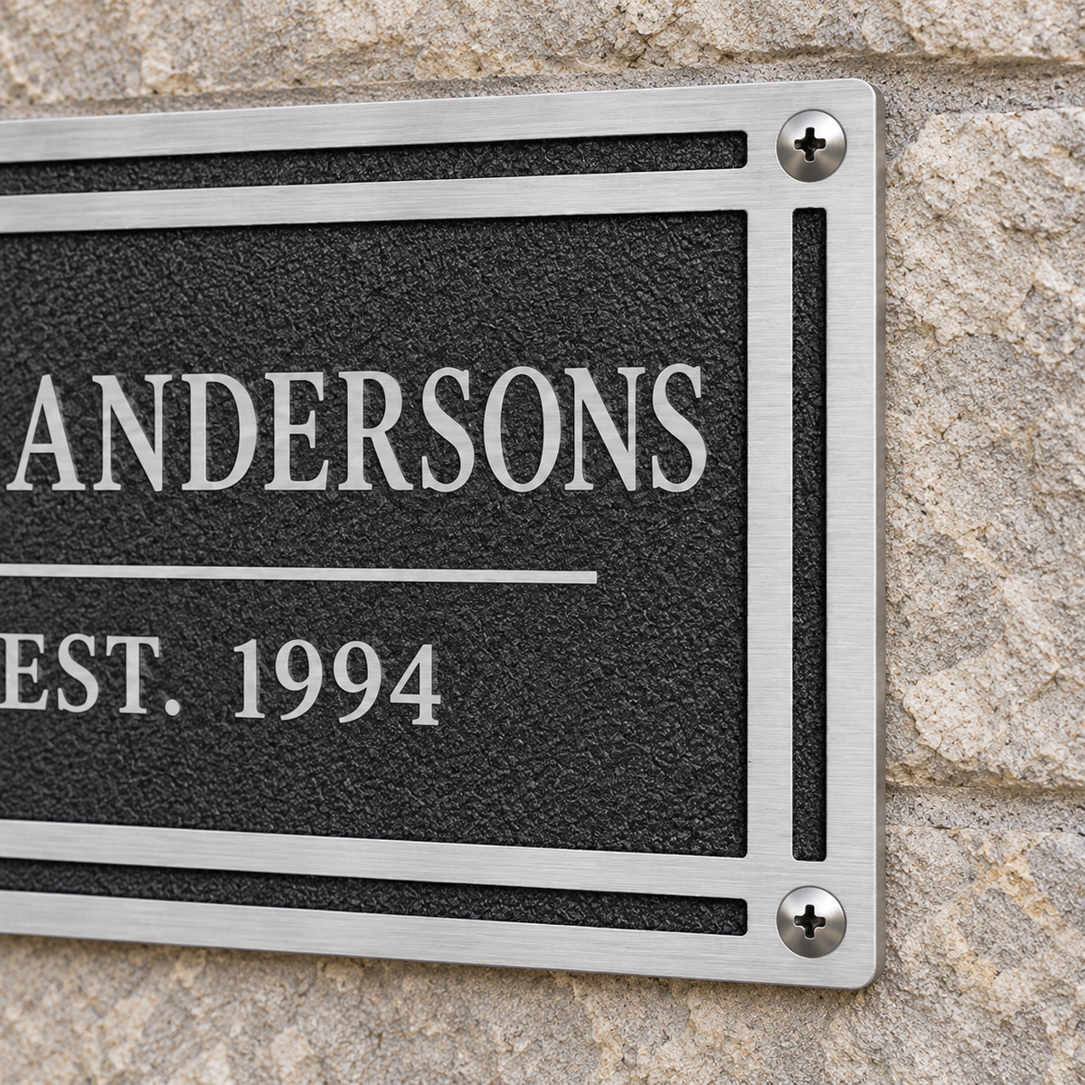 Close-up of Andersons cast aluminum wall plaque mounted to stone with silver screws