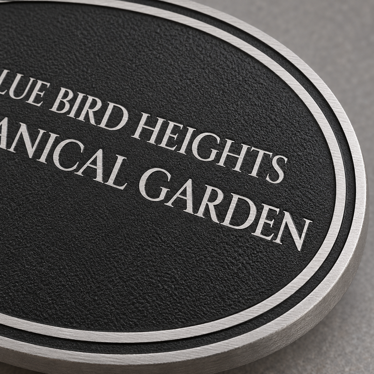 Close-up of textured black cast aluminum oval sign with raised silver border and lettering