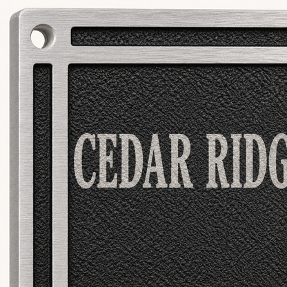 Close-up of textured black cast aluminum plaque with raised silver border and lettering