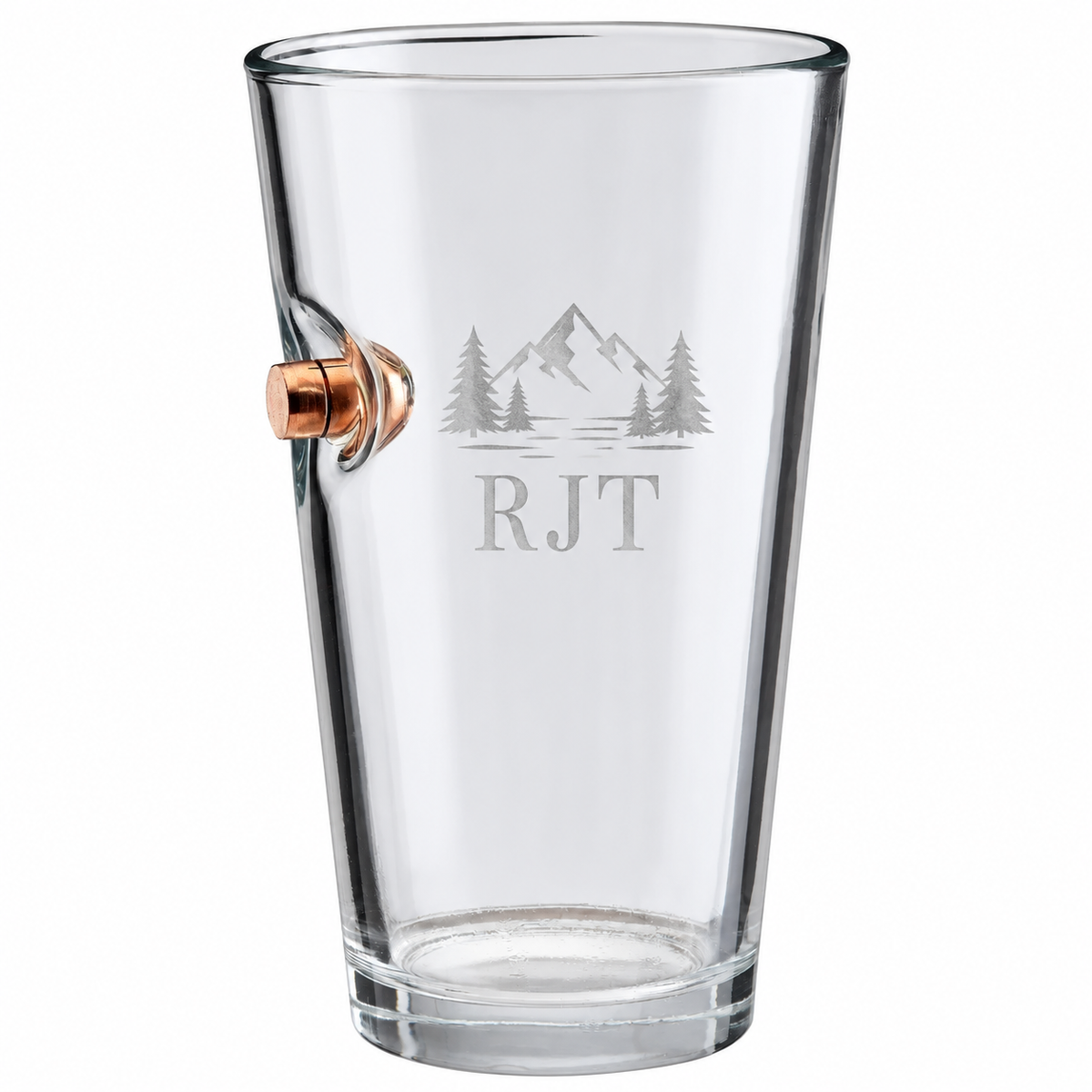 Personalized BenShot bullet pint glass engraved with an RJT mountain design beside a copper bullet on a white background.