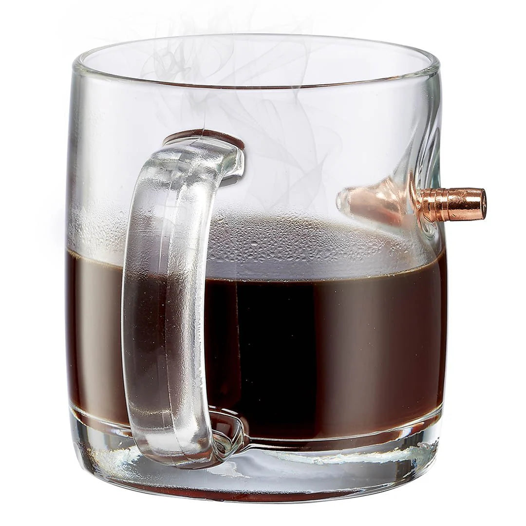 Clear glass mug with a bullet embedment filled with coffee on a white background.