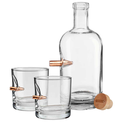 Clear glass decanter and 2 rocks glasses, all with bullet embedment on a white background.