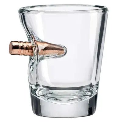 Clear glass shot glass with a bullet embedment on a white background.