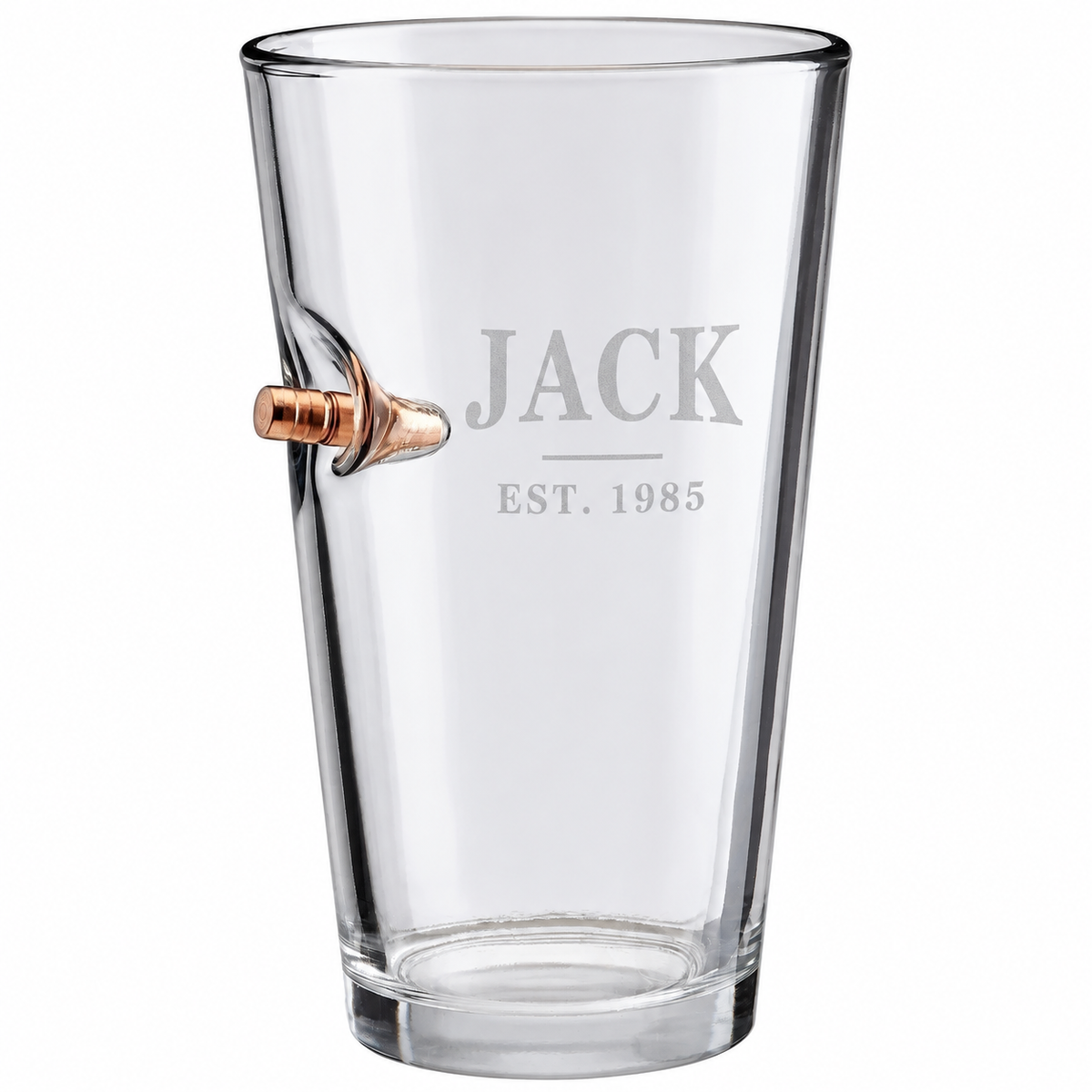 Personalized BenShot bullet pint glass engraved with JACK and EST. 1985 beside a .50 BMG copper bullet on a white background.