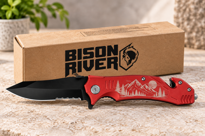 A red and black folding pocket knife with a mountain graphic on the handle, displayed in front of its brown cardboard packaging box printed with the Bison River logo.