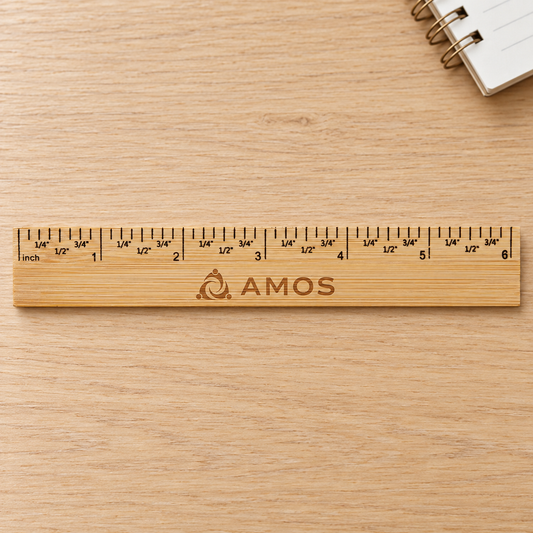 Bamboo ruler engraved AMOS on a pale wood desk.