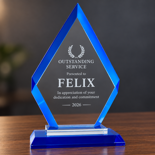 A blue acrylic award trophy plaque on a wooden table, featuring a hexagonal design with a clear center panel engraved with the text 'OUTSTANDING SERVICE Presented to FELIX In appreciation of your dedication and commitment 2026'.