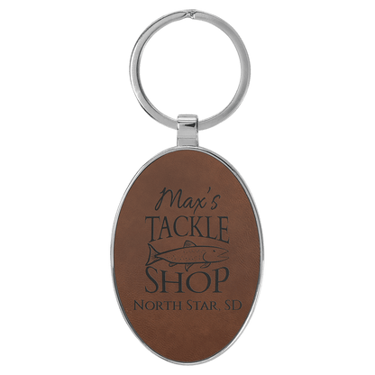 Dark Brown personalized metal-frame oval leatherette keychains with example engraving