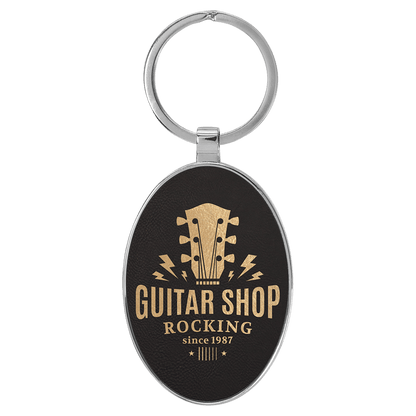 Black/Gold personalized metal-frame oval leatherette keychains with example engraving