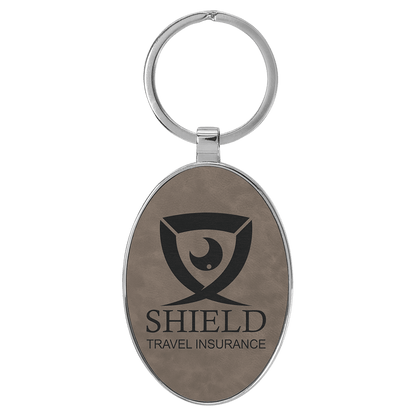 Gray personalized metal-frame oval leatherette keychains with example engraving