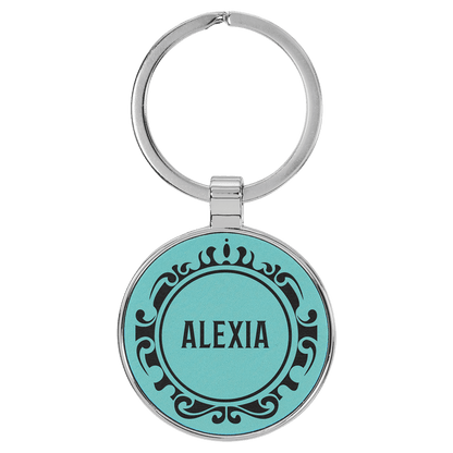 Teal personalized metal-frame round leatherette keychains with example engraving