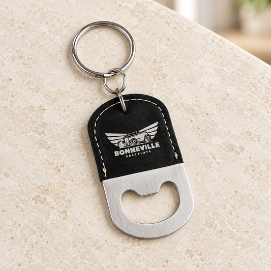 Black and silver oval bottle-opener keychain with BONNEVILLE SALT FLATS sample engraving and silver rings on pale stone.