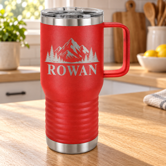 A red insulated travel tumbler with a stainless steel lid and handle, featuring a mountain graphic and the name 'ROWAN' printed on the front, set on a wooden kitchen counter.