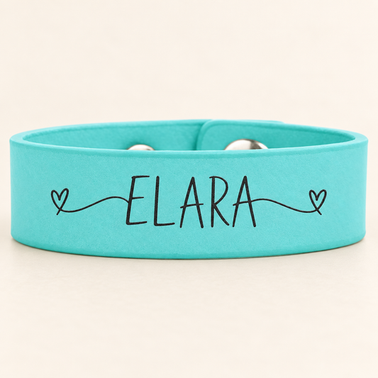 Teal leatherette cuff bracelet with dark ELARA sample engraving and visible snap hardware.