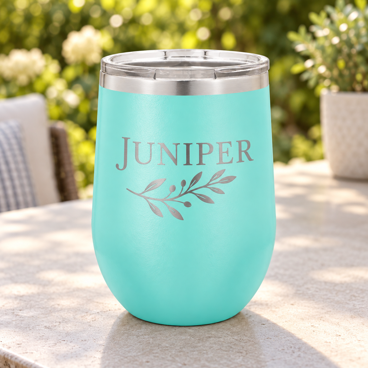 Teal 12 oz stemless wine tumbler with silver JUNIPER leaf engraving and clear lid.