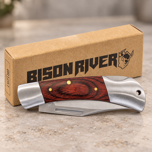 A folding pocket knife with a reddish-brown wood inlay and silver metal blades is displayed in front of its brown cardboard packaging box, which features the 'BISON RIVER' brand name and logo.